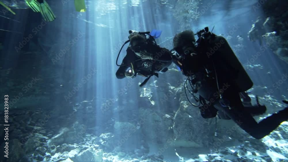 cenote with beautiful blue water, divers underwater,man showing diving signal OK