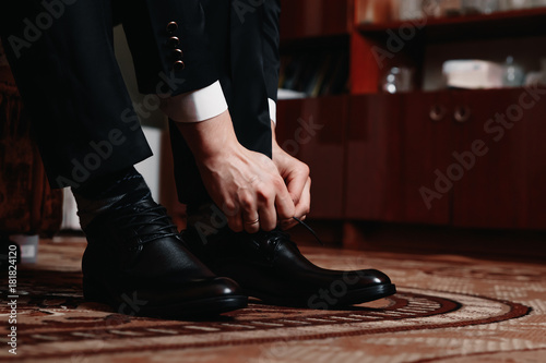 Man is tying his black shoes. Close-up