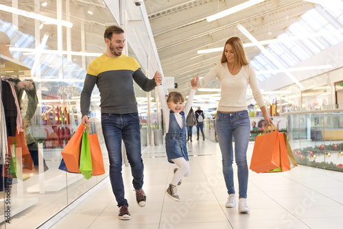 Happy family with child and shopping bags walking along the shopping mall