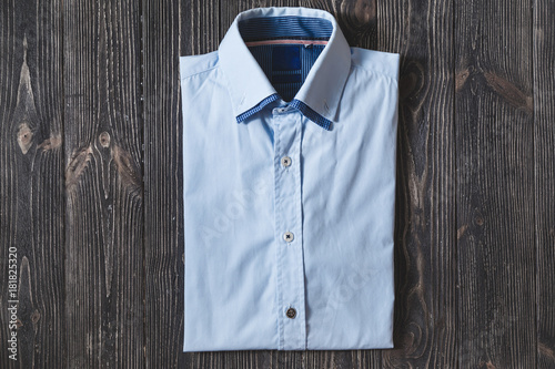 Men's classic blue folded cotton shirt with long or short sleeve on black brutal background.