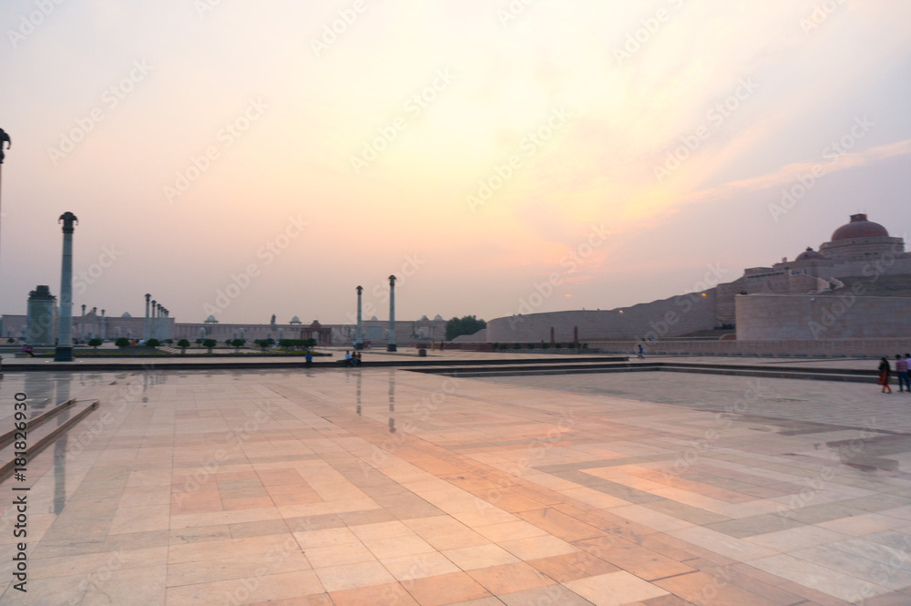 Wide angle shot of Ambedkar park with the beautiful orange light of sunset. The landscape of the park and the stupa in the background show off the huge size of the park