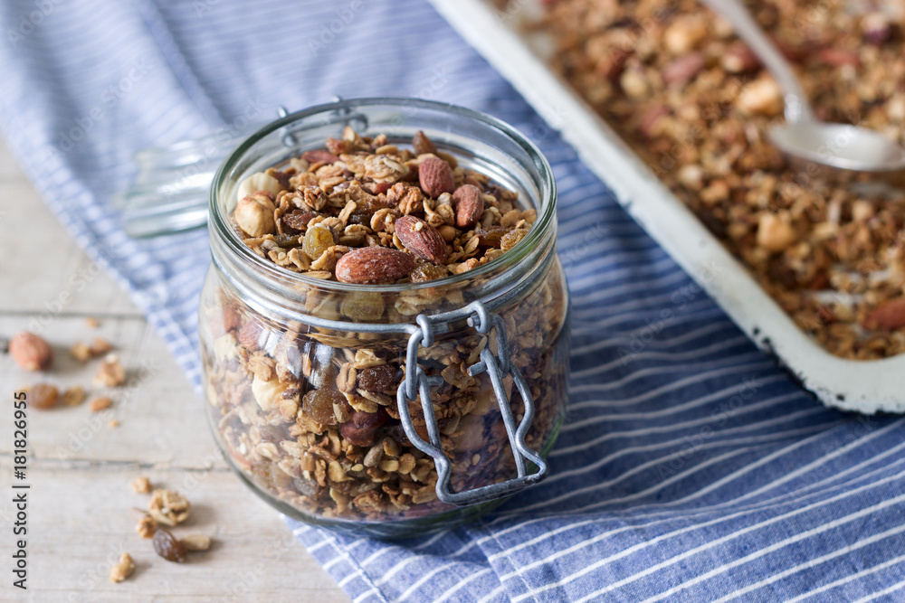 Homemade granola in a glass jar and on a baking sheet. Rustic style. Homemade granola in a glass jar and on a baking sheet. Rustic style.