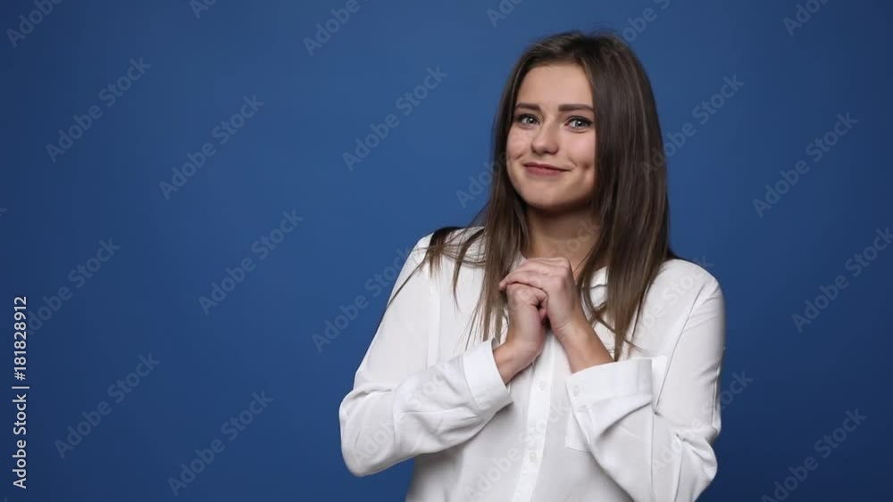 Smiling girl playing hide and seek while covering her eyes with palms isolated over blue background Smiling girl playing hide and seek while covering her eyes with palms isolated over blue background