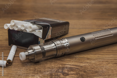 Popular vaping mod device.Upgrade parts for a modern vaporizer electronic cigarette device,parts.A new model of the device, the micro-coil clearomizer, on wooden background.