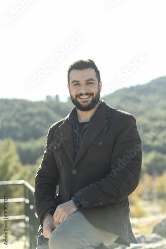 Bearded man posing in outdoors portrait looking at camera and smiling with casual clothing
