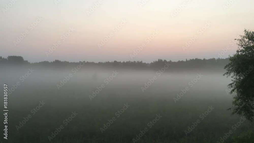 Fog hovering over field at dusk with colorful amber sky above and camera panning slowly right. Fog hovering over field at dusk with colorful amber sky above and camera panning slowly right.