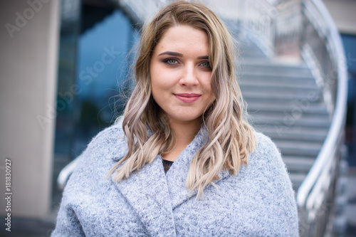 Free Download A woman of plus size, American or European appearance walks in the city enjoying life. A young lady with excess weight, stylishly dressed in coat at the center of the city. Natural beauty - GFXLoad