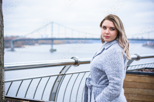 A woman of plus size, American or European appearance walks in the city enjoying life. A young lady with excess weight, stylishly dressed in coat at the center of the city. Natural beauty © T.Den_Team