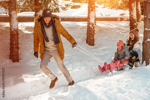 father taking family on a sledge snow ride photo