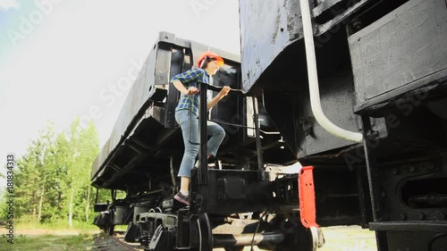 Wallpaper Mural A young woman railway worker in an orange helmet get down the stairs from the cargo wagon then walking beside the train past the camera Torontodigital.ca