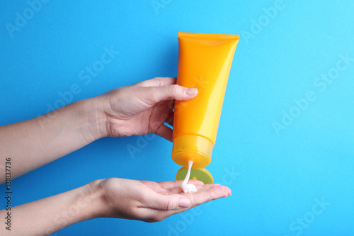 Female hand holding sunscreen cream on blue background photo