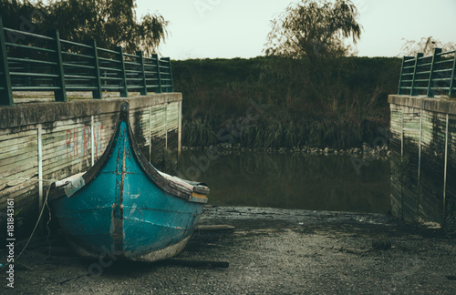Resting old blue wooden boat, dry docked by the river.