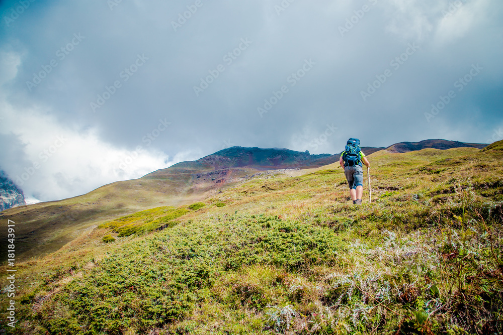 Young men looking to the peak of misty mountain..It looks impossible to reach the peak. Men do not get up and move up to the peak. Caucasus Mountains.  Svaneti, Geogria.