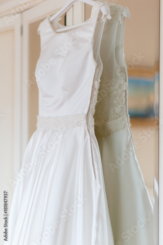 Wedding dress hanging on the wardrobe in the bedroom. The wedding collection. Classic expensive dress for a wedding or celebration in the room of an expensive hotel. Closeup
