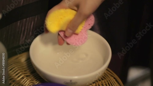 Professional cosmetician squeezes cosmetic sponge to clean the face of a girl in a spa salon photo