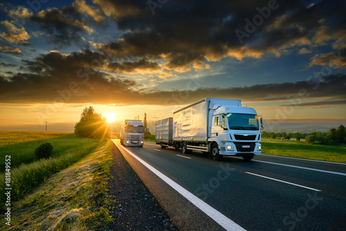 Overtaking trucks on an asphalt road in a rural landscape at sunset photo