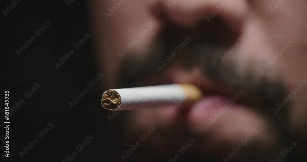 Close Up Man Lights Cigarette and Smokes. a close up view of a mans lower face with a cigarette and a lighter lights it as he smokes