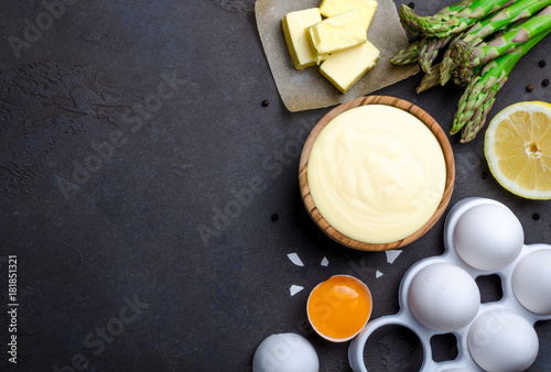 Basic french sauce hollandaise in a wooden bowl with ingredients photo