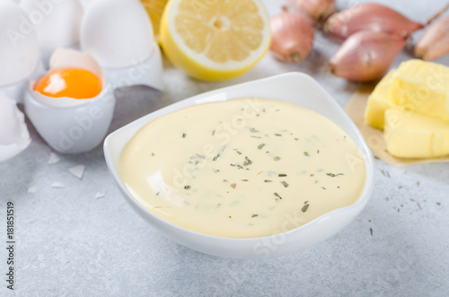 Basic french sauce bearnaise in a white bowl with ingredients, b
