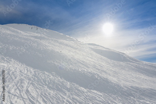 Advanced black steep ski trail, with sun behind the mountain