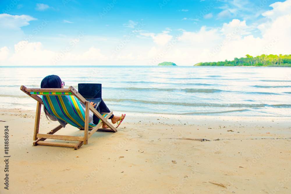 Business woman using a laptop beside the beach