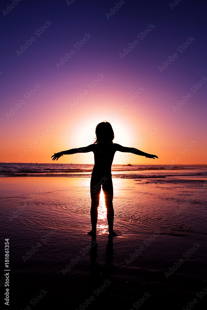 Silhouette of a girl  with open arms in the ocean, at sunset.