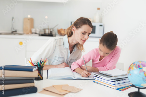Mom helps my daughter do her homework in the kitchen.