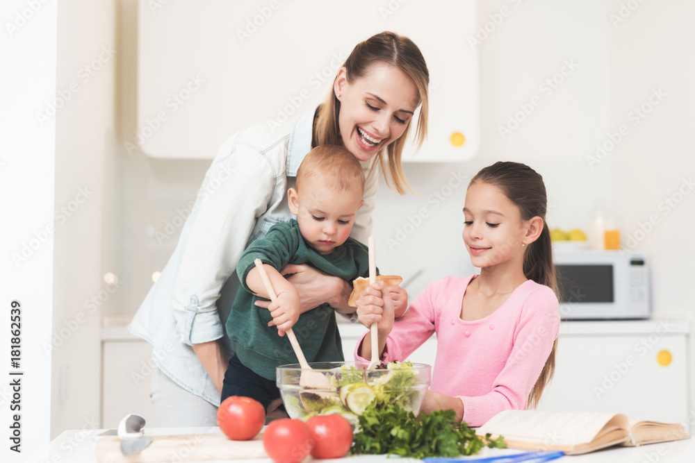 Mom and daughter have fun while preparing a salad. They are in a bright kitchen. Mom and daughter have fun while preparing a salad. They are in a bright kitchen.