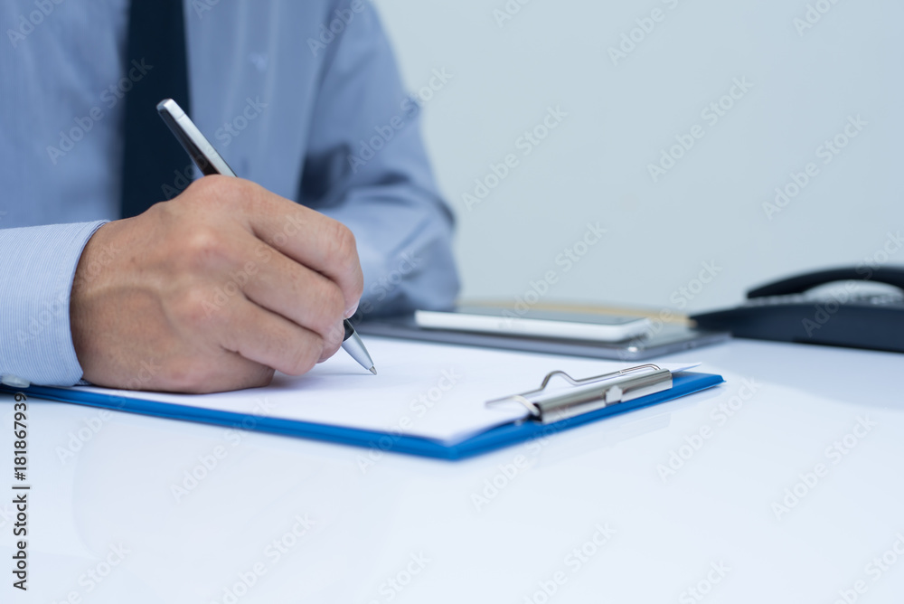 Fototapeta premium Businessman writing on note pad
