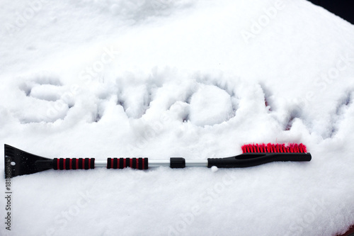 Closeup photo of black brush lying on car covered in snow .
