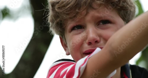 Child crying in tears. Real life authentic candid sobbing of a tearful child on top of a tree. Inconsolable crying young boy is sobbing in 4k