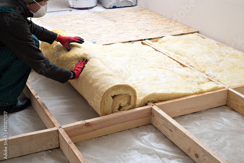 Caucasian Construction Worker with Roll of Insulating Material, Floor Insulating by Mineral Wool.