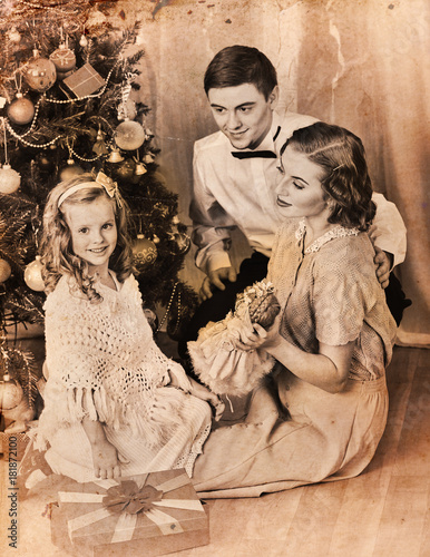 Christmas family photo with mother, father and girl. Black and white Xmas vintage image with child by home interior.