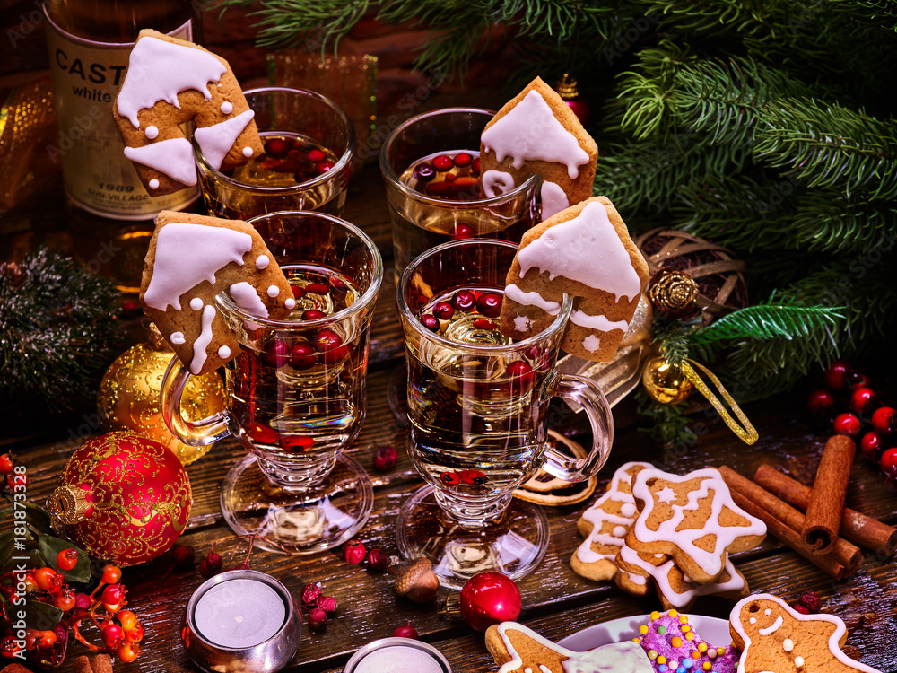 Christmas table decorations with glasses of punch and gingerbread cookies, bottle of wine in background. Xmas arrangement top view.