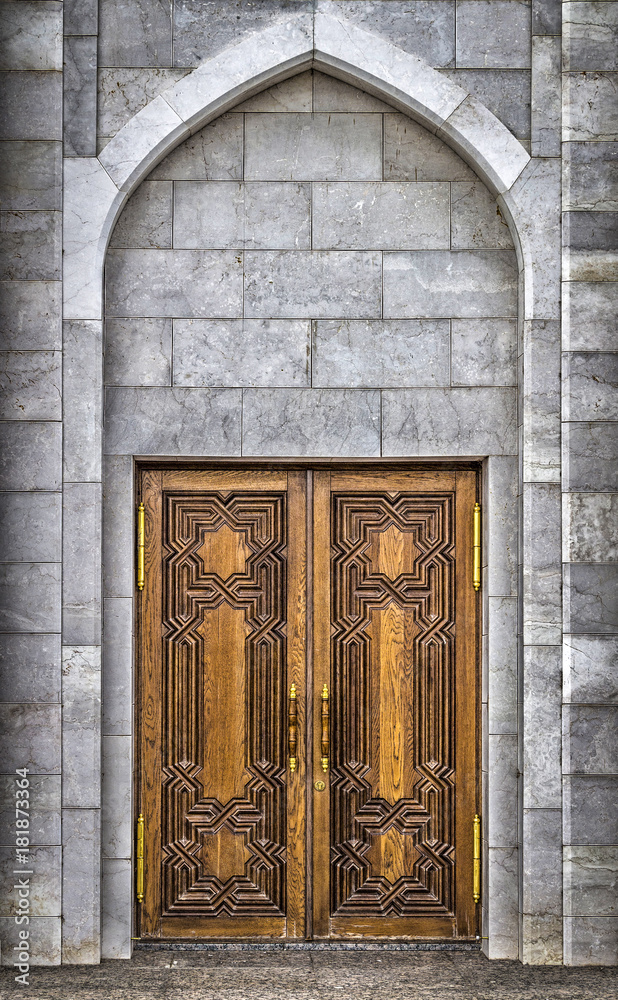 Wooden carved door to the mosque from white stone.