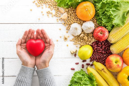 Woman hands showing red heart ball with healthy food aside