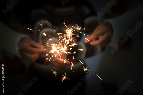 Bright festive Christmas or New Year sparkler in hand toning, showing group of friends having fun. photo