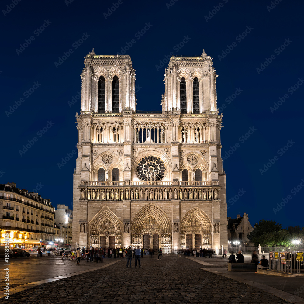 Paris, France - October 17, 2017: Night view of West facade at cathedral Notre Dame de Paris. Unidentified people present on picture. Copy space in sky.