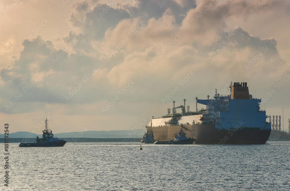 LNG TANKER- The big tanker maneuveres in the harbor secured by tugs
