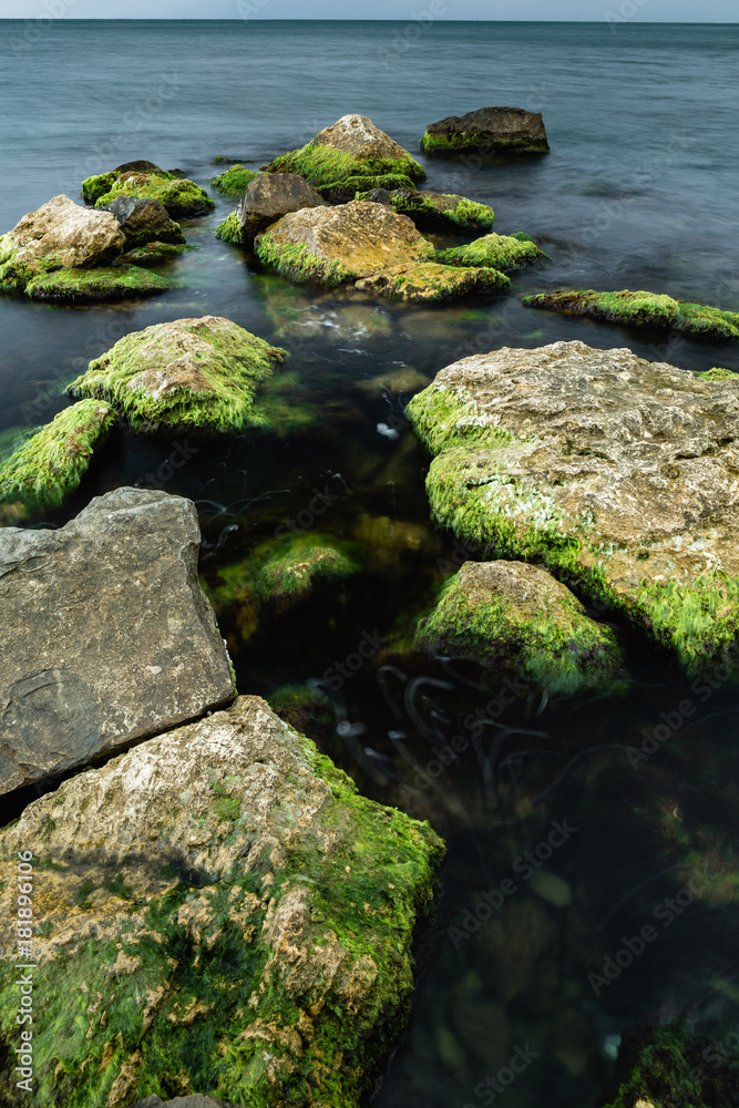long exposure of sea and rocks covered with green algae