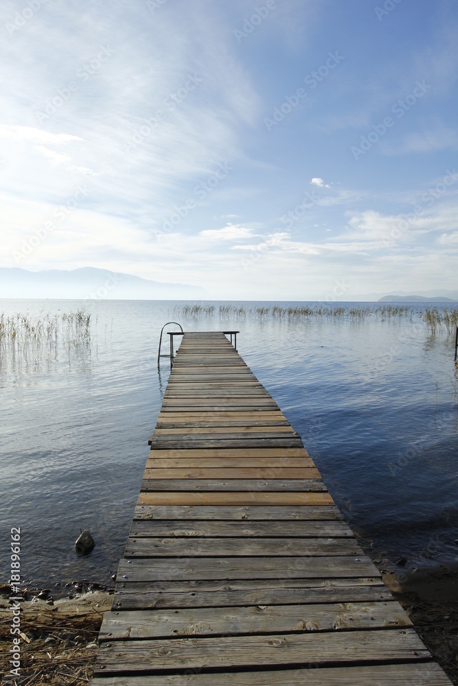 Old wooden pier by the Ohrid Lake with a cloudy sky on an autumn day