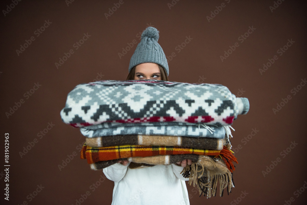 Woman looking out from pile of blankets - obrazy, fototapety, plakaty 