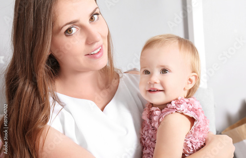 Young mother holding cute baby at home