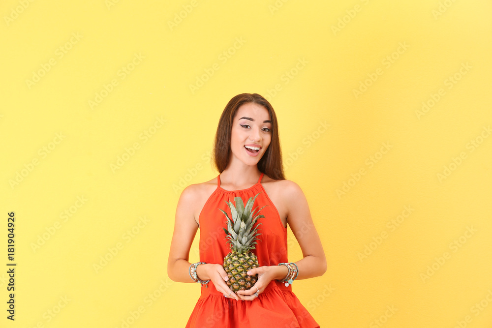 Attractive hipster girl posing with pineapple on color background