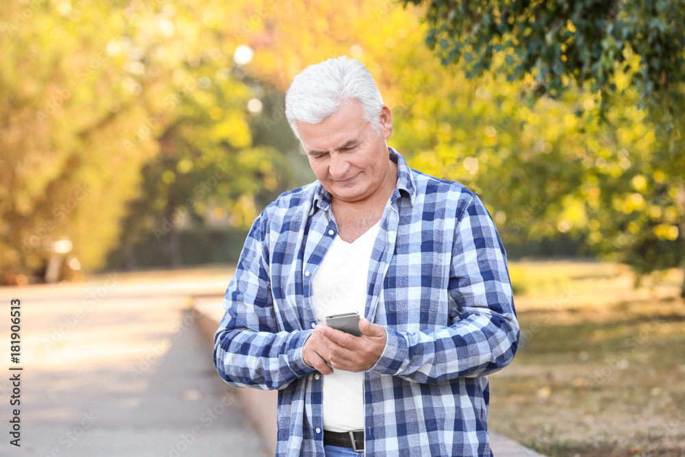 Handsome mature man with cell phone in park Handsome mature man with cell phone in park