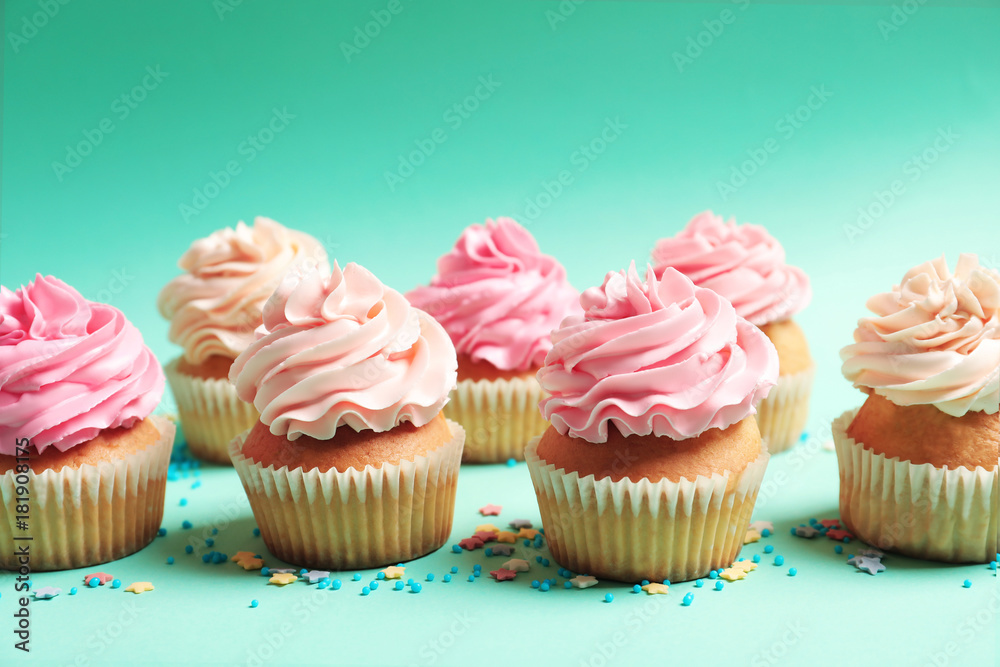 Many yummy cupcakes on color background