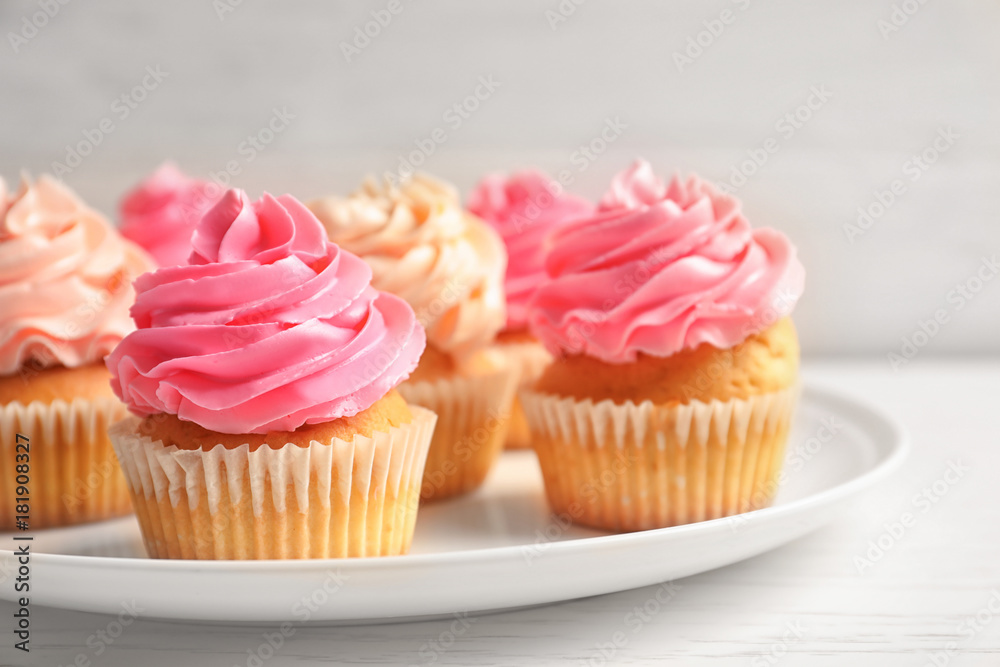 Plate with yummy cupcakes on wooden table