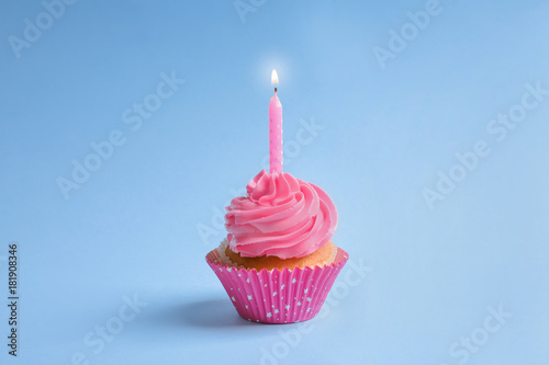 Yummy cupcake with candle on color background