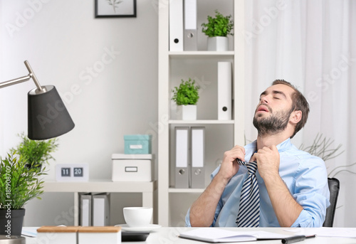 Obraz na plátně Young man feeling hot in office
