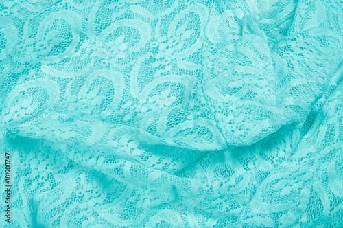 Texture, fabric, background. Lacy turquoise fabric, lace. A thin open fabric, usually cotton or silk, made by a loop, twisting or knitting on patterns and is used specially for trimming clothes.